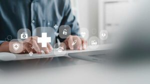 médecin utilisant un ordinateur portable avec des icônes de soins de santé - congé supplémentaire de naissance - Activ Consulting