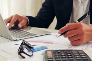 mains d'une femme d'affaires ou d'une comptable utilisant une calculatrice - externalisation de la paie - Activ Consulting