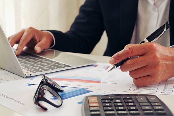 mains d'une femme d'affaires ou d'une comptable utilisant une calculatrice - externalisation de la paie - Activ Consulting